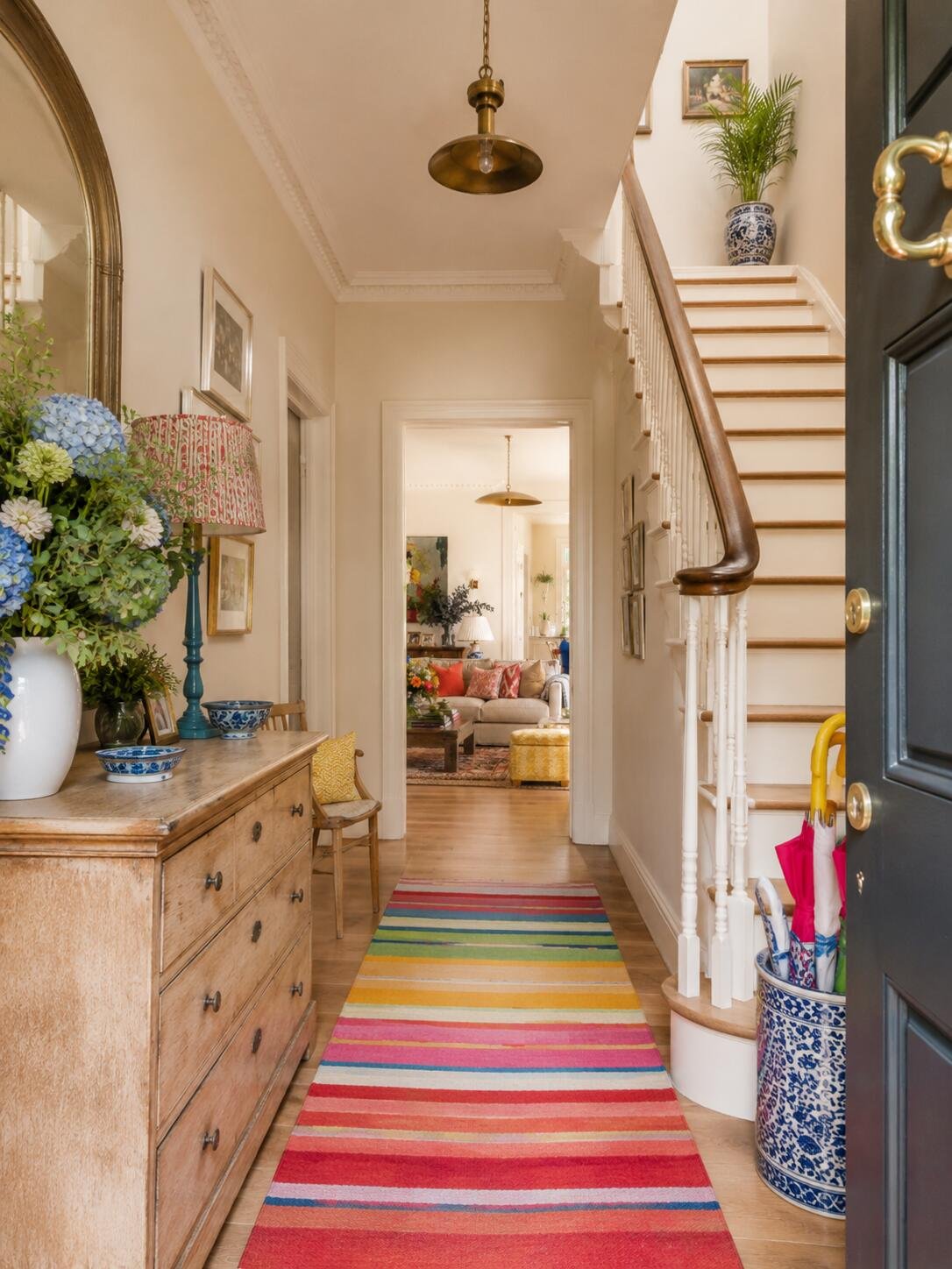 Bright cottage hallway featuring staircase, brass pendant light, and blue ceramic decor