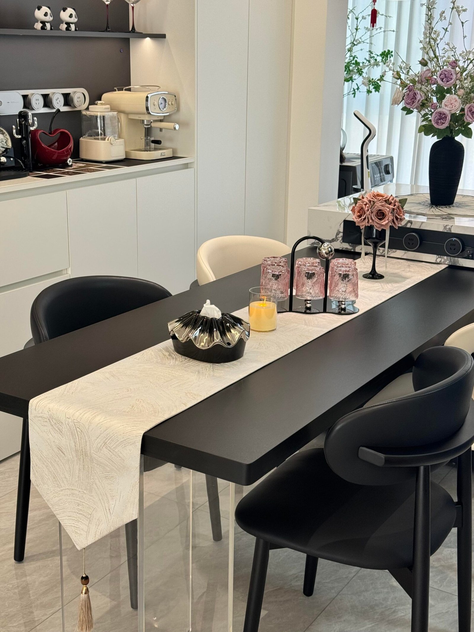 Elegant black dining table with soft neutral decor and warm pendant lighting