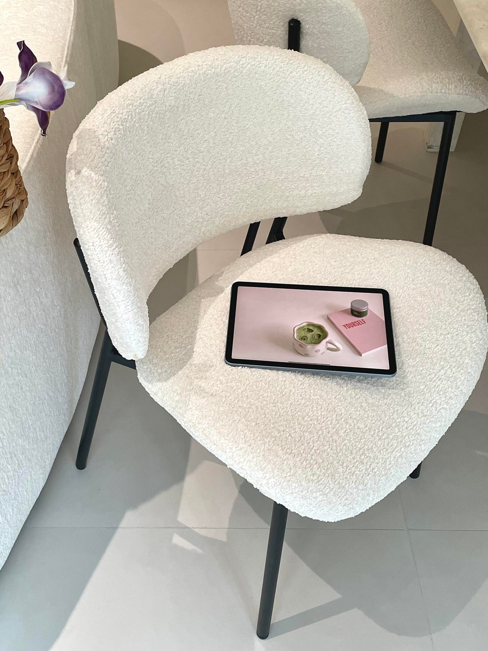 Cream upholstered dining chairs paired with an oval stone dining table in a minimalist kitchen.