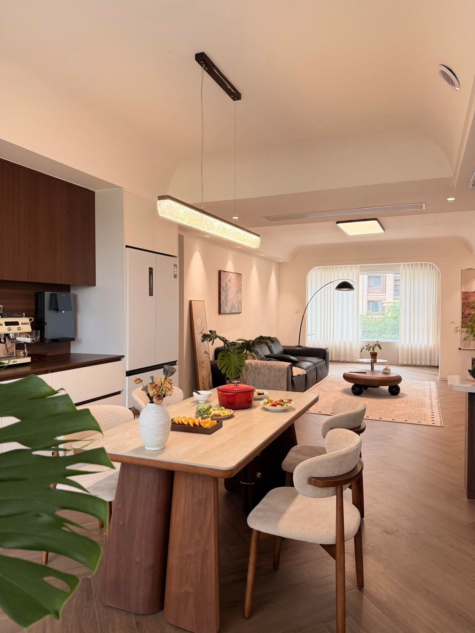 Rectangular wood dining table with cushioned chairs in a bright modern interior.
