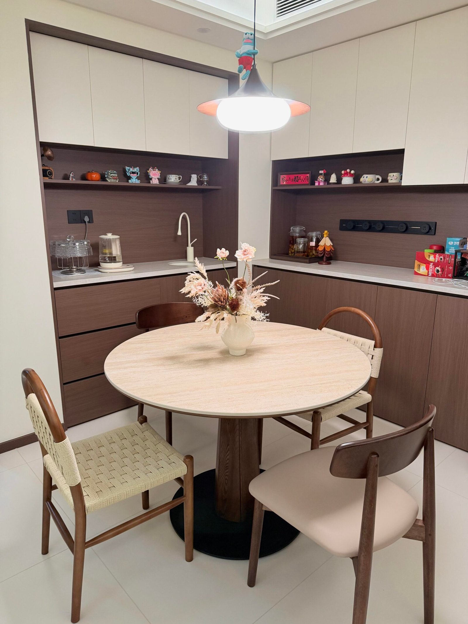 Modern round dining corner with wood textures and a floral centerpiece.