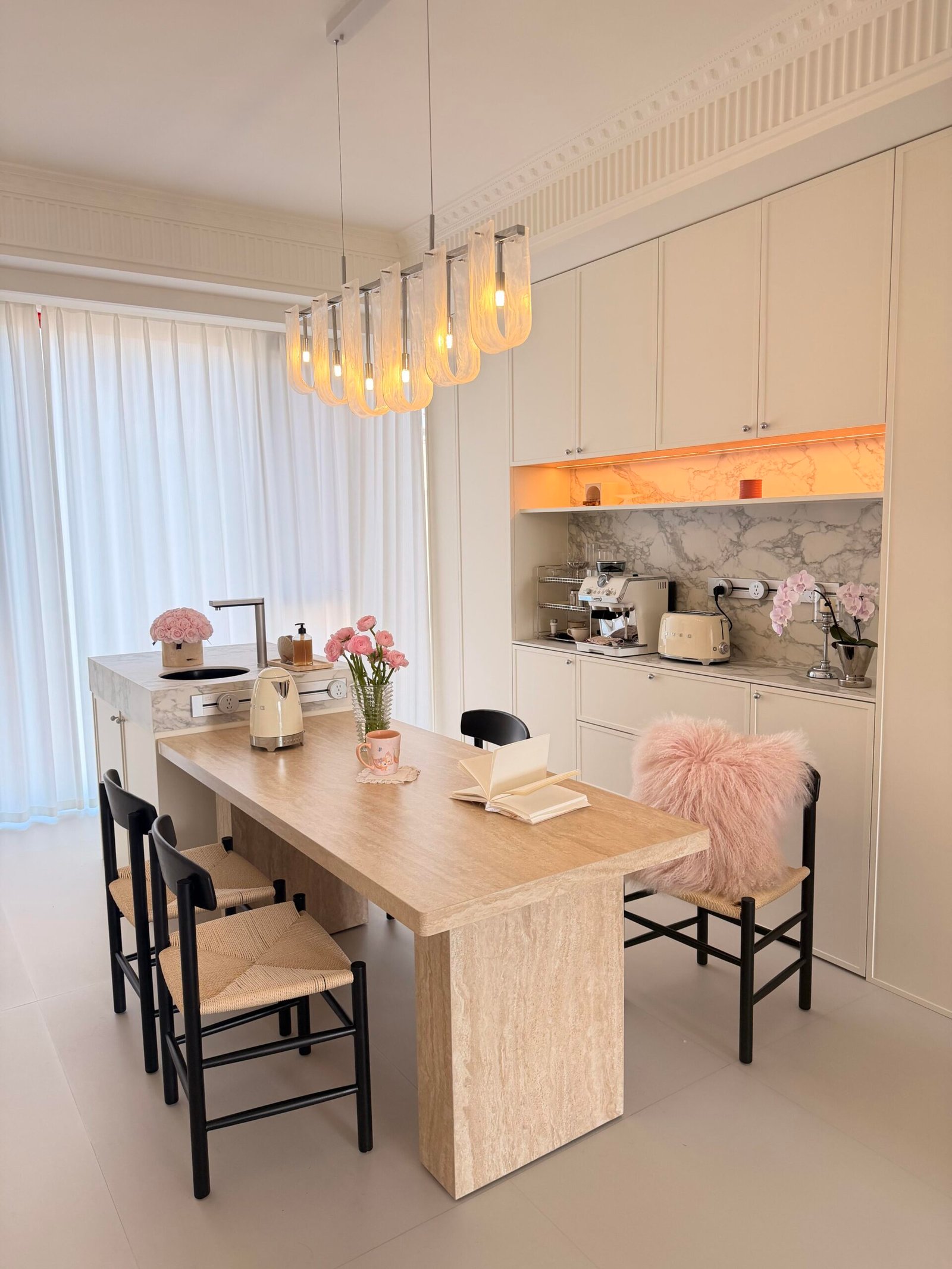 Marble dining table with sculptural chairs and a statement chandelier overhead