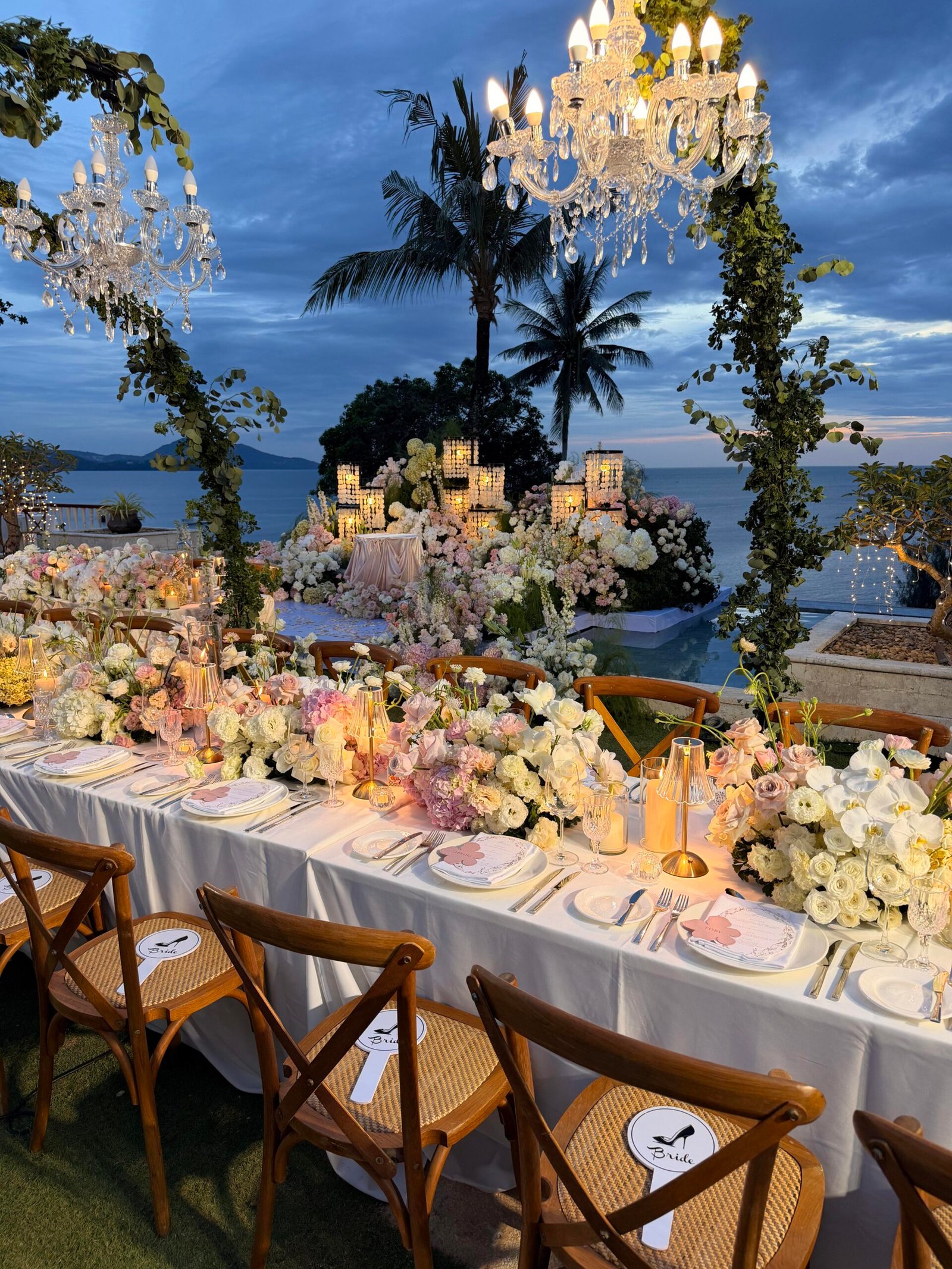 Tropical sunset wedding reception with crystal chandeliers over palm trees