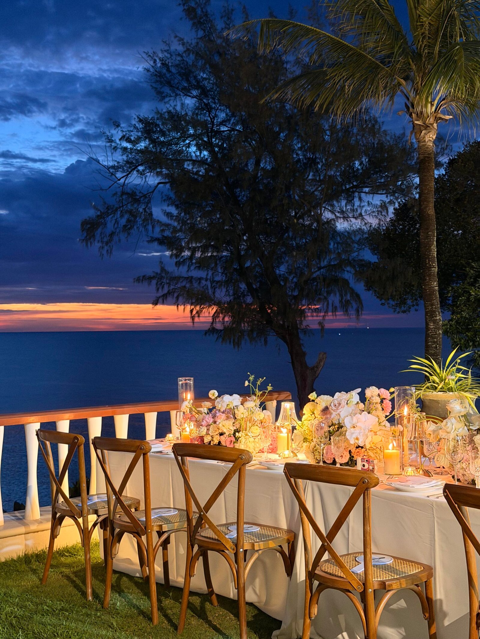 Long banquet table setup with blush and ivory floral runner at beach wedding
