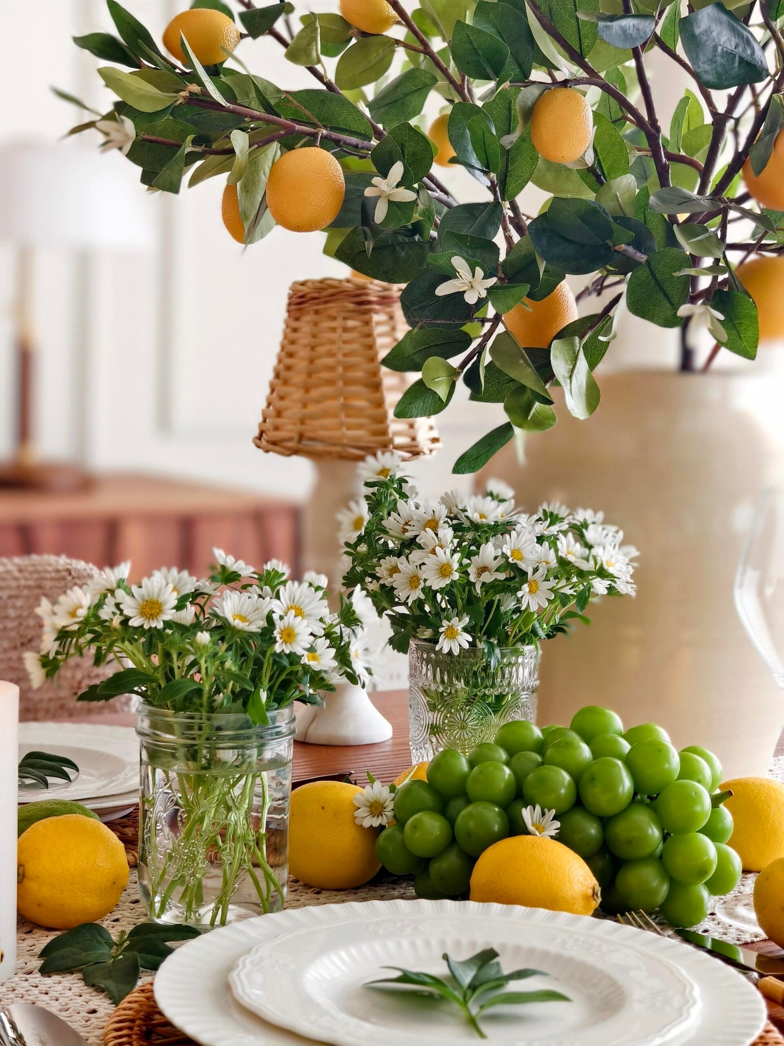 Dining table decor ideas with faux lemon tree branch and daisy-filled mason jars
