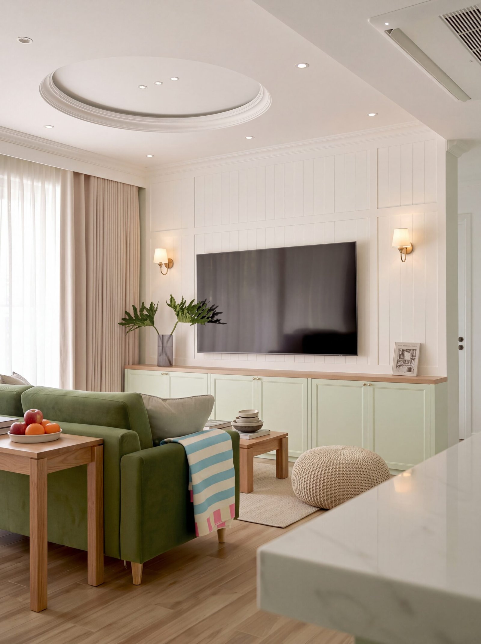 Sage green living room with built-in cabinetry, wall-mounted TV, and round tray ceiling.